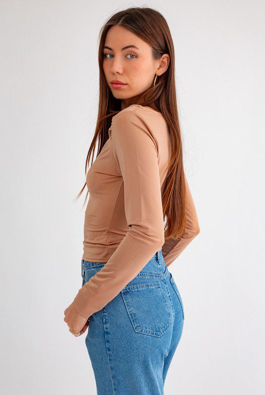 Woman in beige top and blue jeans.