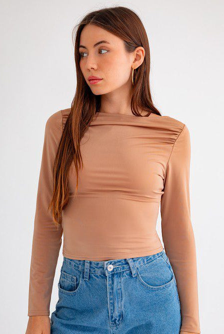 Woman in nude long-sleeve top and jeans.