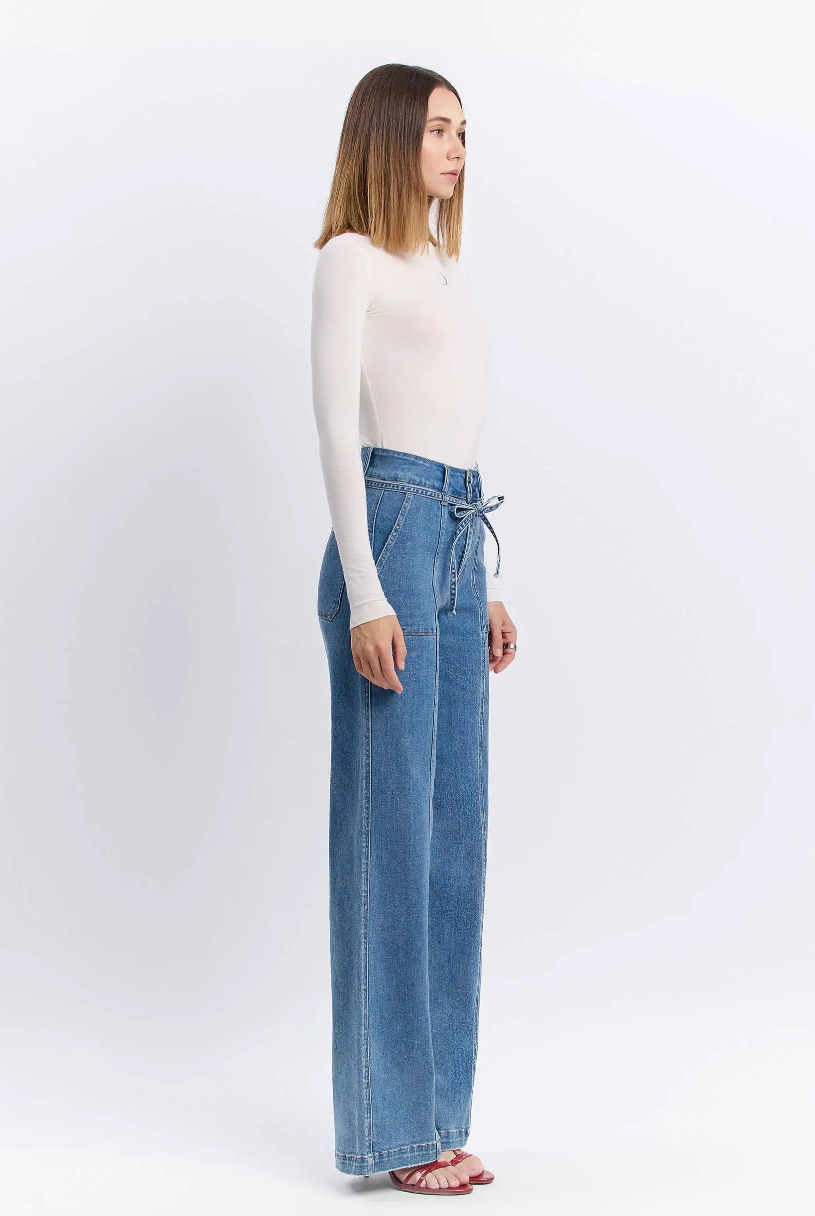 Vervet Olivia Super High Rise Wide Leg Jeans with Tie Waistband in Lush Life denim, side profile on a model wearing a white top.