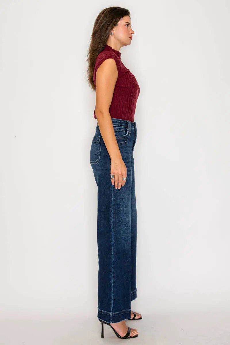 Side view of a woman wearing ARTEMIS VINTAGE tummy-control high-rise A-line wide-leg jeans in dark stone wash.