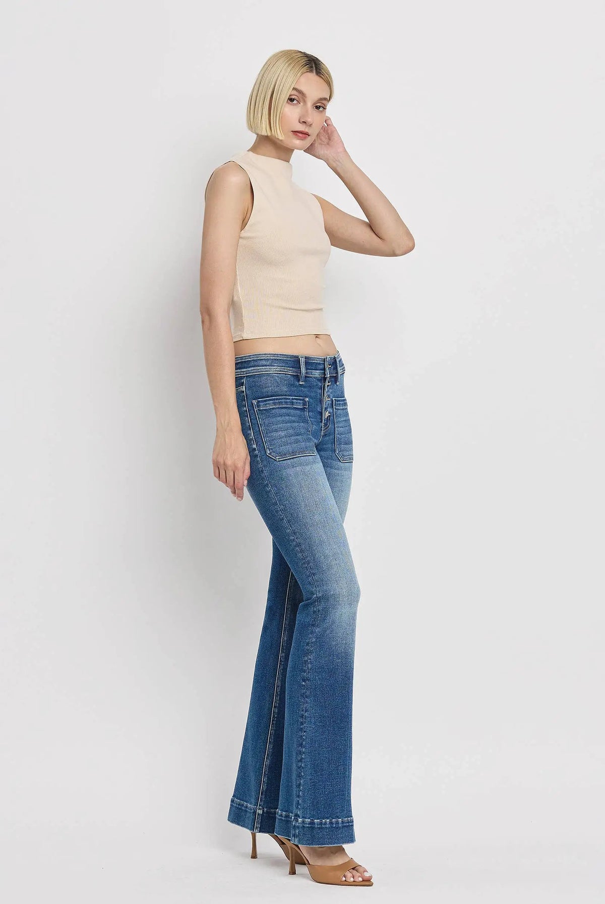 Vervet Alison mid rise flare jeans in blue with patch pockets and trouser hem detail displayed by model on white background.