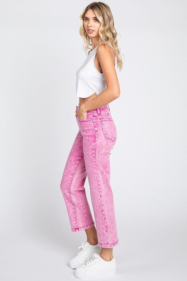 A woman wearing pink jeans and white tank top.