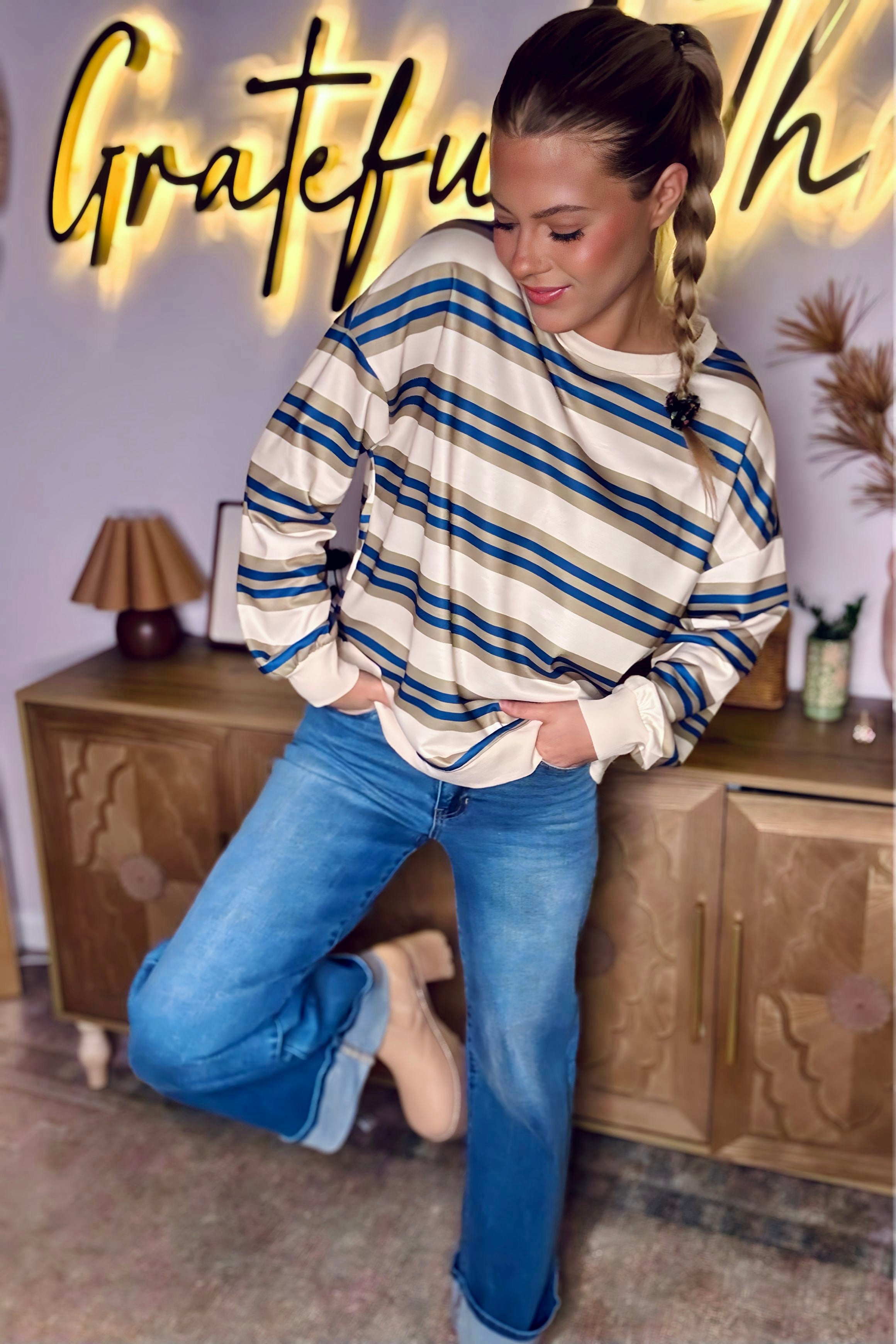 Women’s khaki stripe drop shoulder pullover sweatshirt styled with blue jeans and boots.