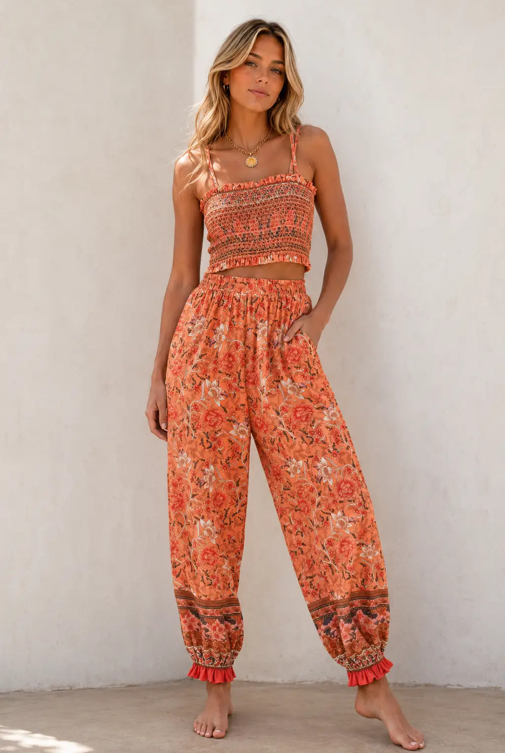 Orange floral two-piece set featuring a smocked ruffle crop top and matching high-waisted boho pants with ruffled ankles.