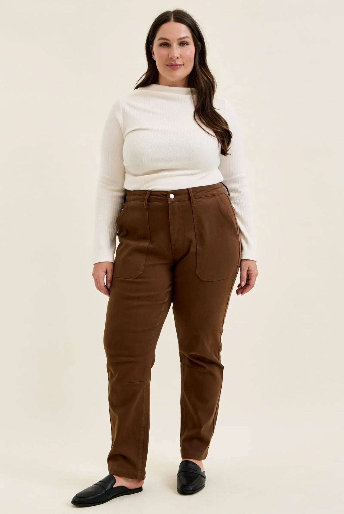 Plus size model wearing mahogany high-waist stretch jeans with utility pockets and slim-straight leg in double-rolled cuffs.