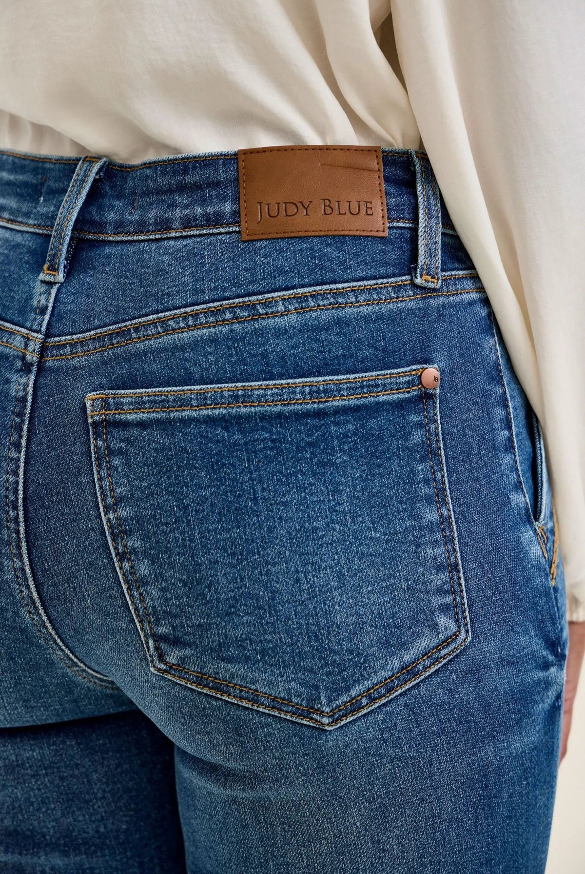 Judy Blue jeans, blue denim with yellow stitching and brown leather patch on waistband.