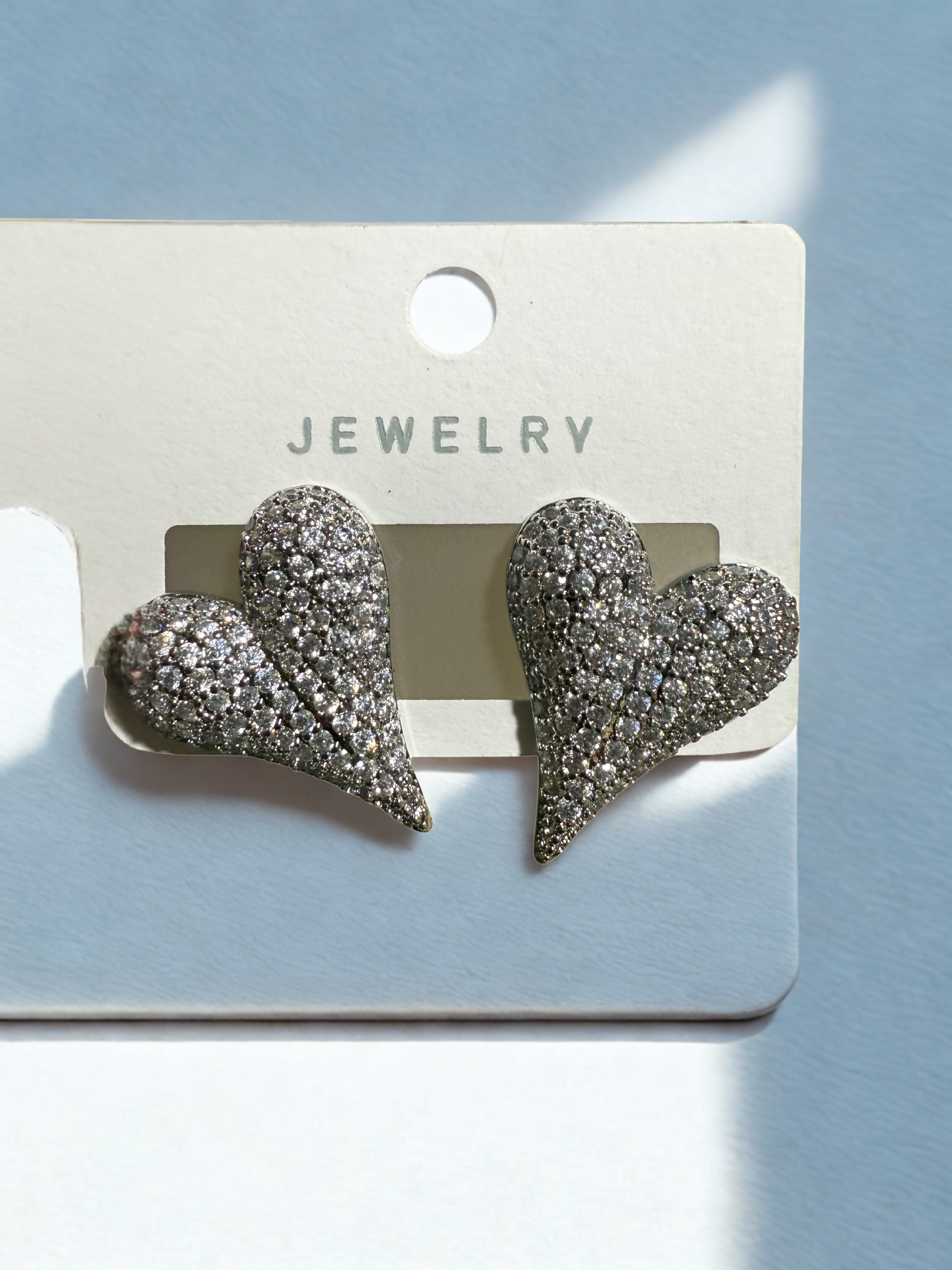 Heart-shaped earrings on a jewelry card with a light blue background