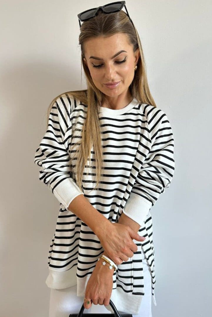 A woman in black and white striped shirt holding a knife.