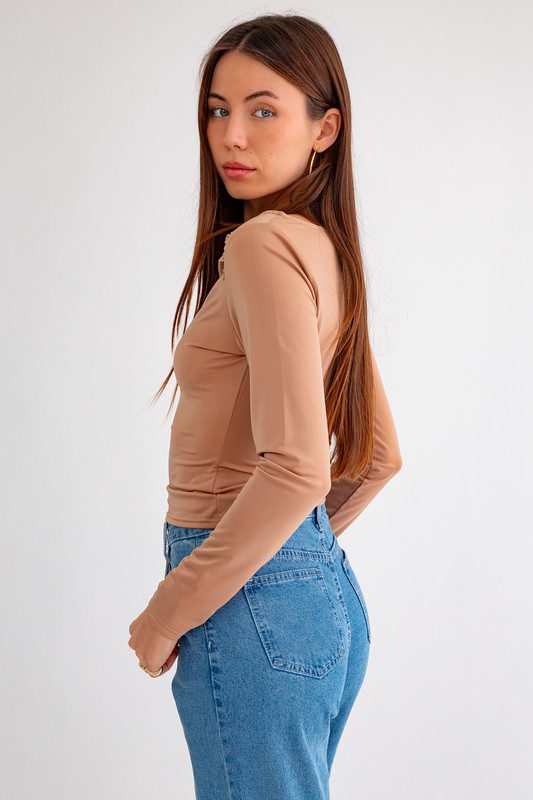 Woman in beige top and blue jeans.