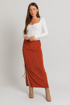 Woman in white top and rust skirt.