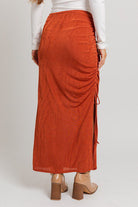 Rust side-tied maxi skirt with slit.