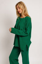 Woman in green henley top and pants.