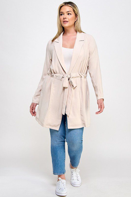 Beige belted jacket, plus size model.