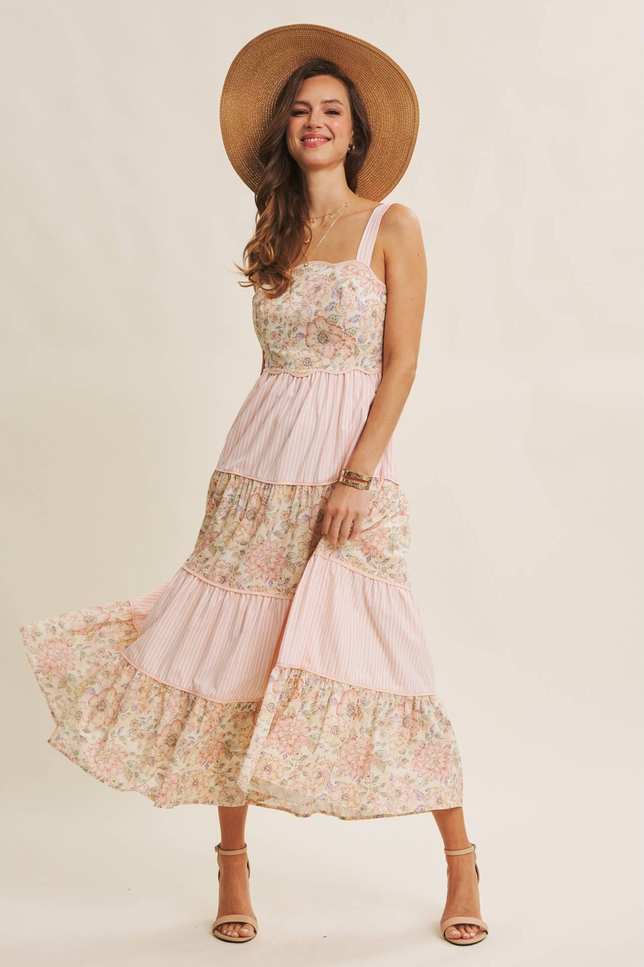 Woman wearing a floral dress and straw hat on a beige background