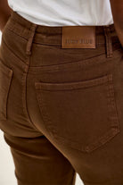Back view of Judy Blue high-waist mahogany stretch jeans featuring a leather brand patch and tailored rear pockets.