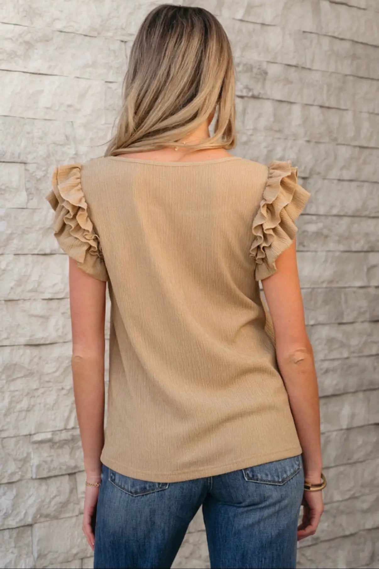 Back view of a light mocha ruffled tiered sleeve square neck textured top paired with blue jeans.