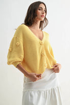Textured LT.YELLOW knit cardigan with 3D floral buttons, worn by a woman.
