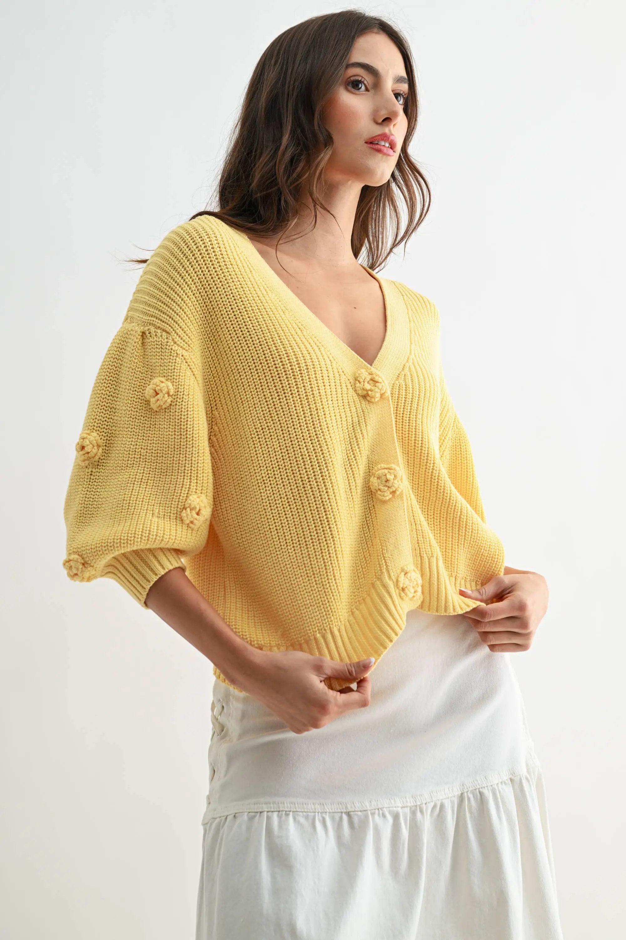 Textured LT.YELLOW knit cardigan with 3D floral buttons, worn by a woman.
