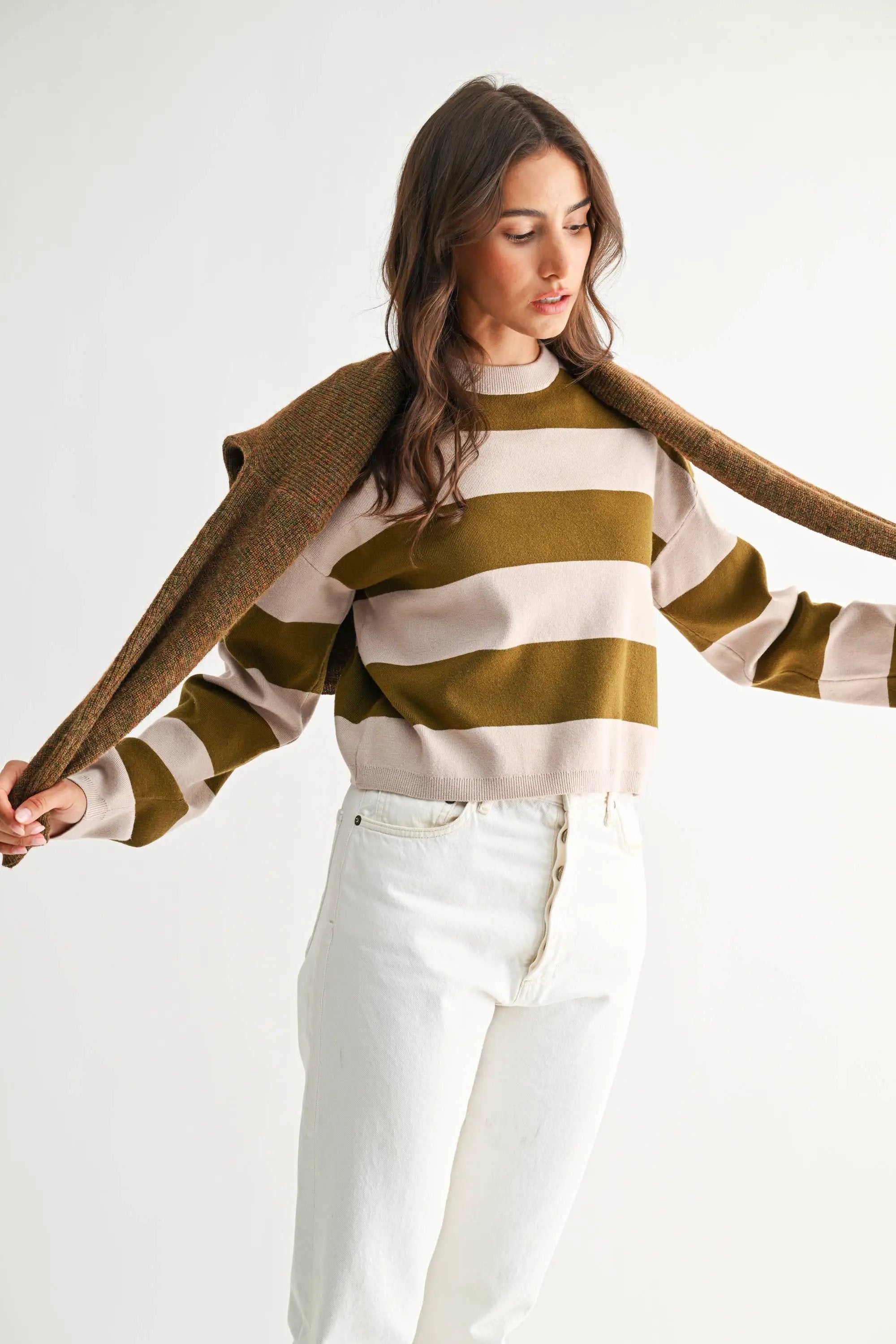 Model wearing a light taupe and olive bold stripe crewneck sweater with cream bands, relaxed fit.