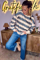 Women’s khaki stripe drop shoulder pullover sweatshirt styled with blue jeans and boots.