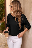 A woman holding a cup of coffee while leaning on the wall.