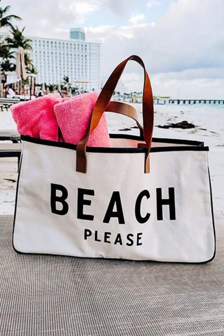 A beach bag with towels on the ground.