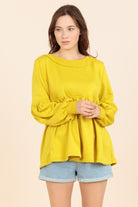 A woman wearing a yellow top and jeans.