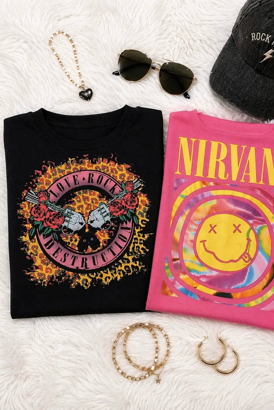 Pink Nirvana graphic tee with tie-dye smiley face displayed alongside a black rock print shirt and accessories for a grunge aesthetic.