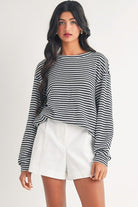 A woman wearing white shorts and black striped shirt.