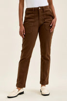 Mahogany high-waist skinny jeans with slim straight leg, knee darts, and double-rolled cuff paired with white loafers.