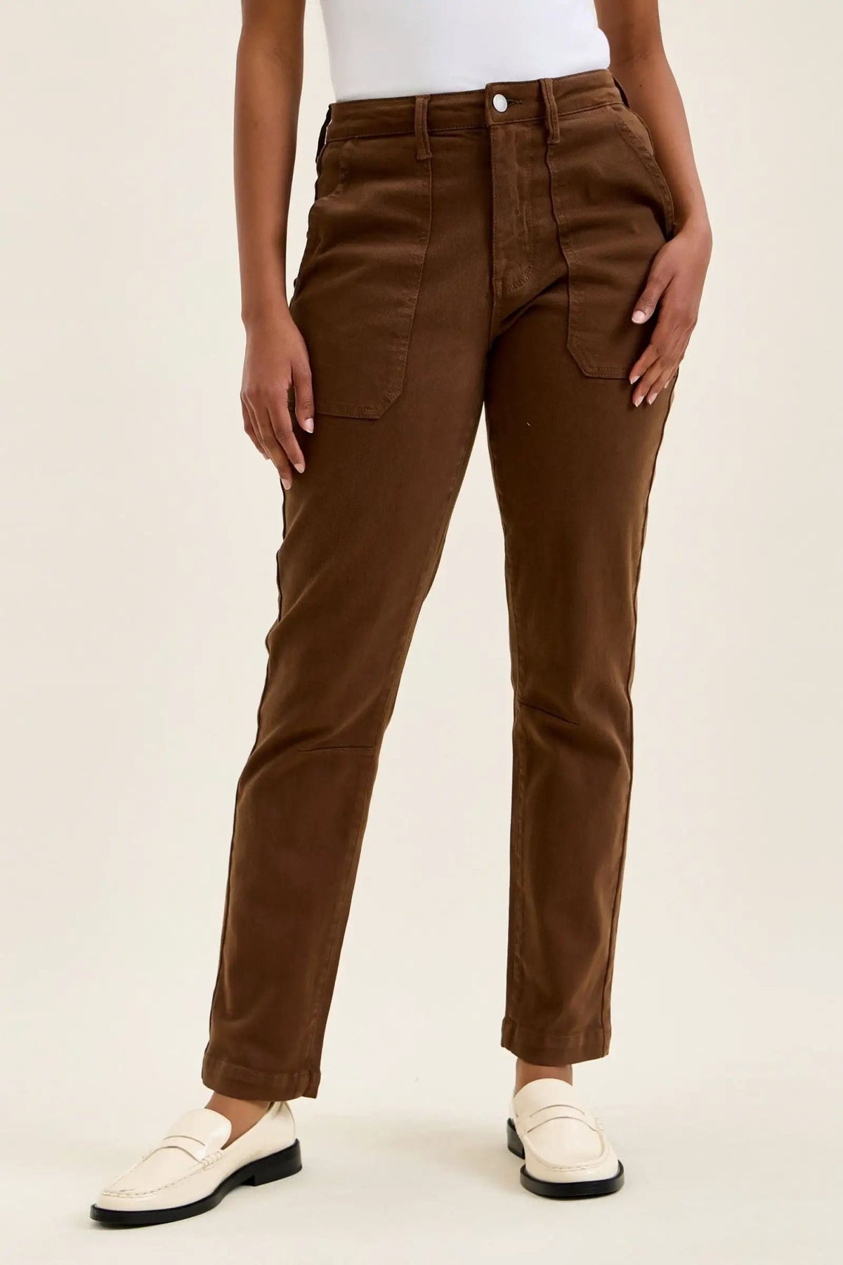 Mahogany high-waist skinny jeans with slim straight leg, knee darts, and double-rolled cuff paired with white loafers.