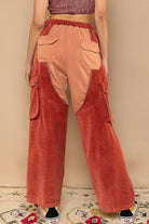 Red corduroy cargo pants with patches.