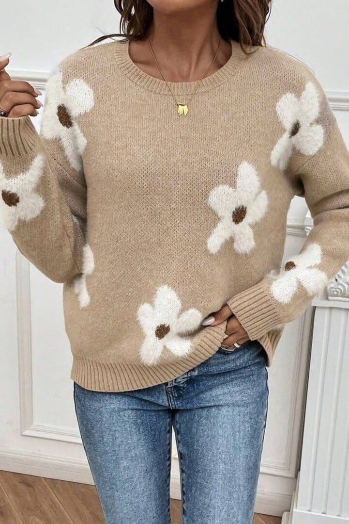 A woman wearing jeans and a sweater with white flowers.