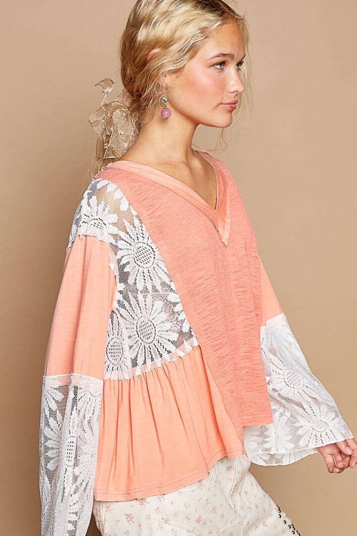 Peach blouse with white lace details.