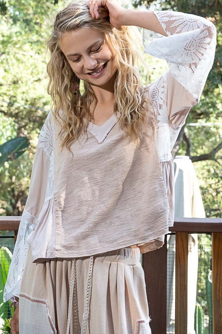 Woman in beige lace-trimmed blouse and skirt.