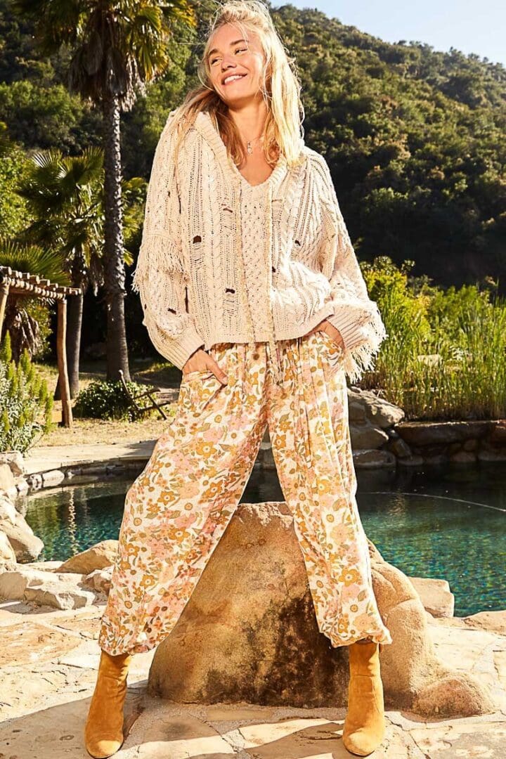 Woman in floral pants and cream sweater.