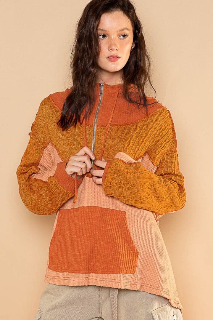 Woman in orange color-blocked hoodie.