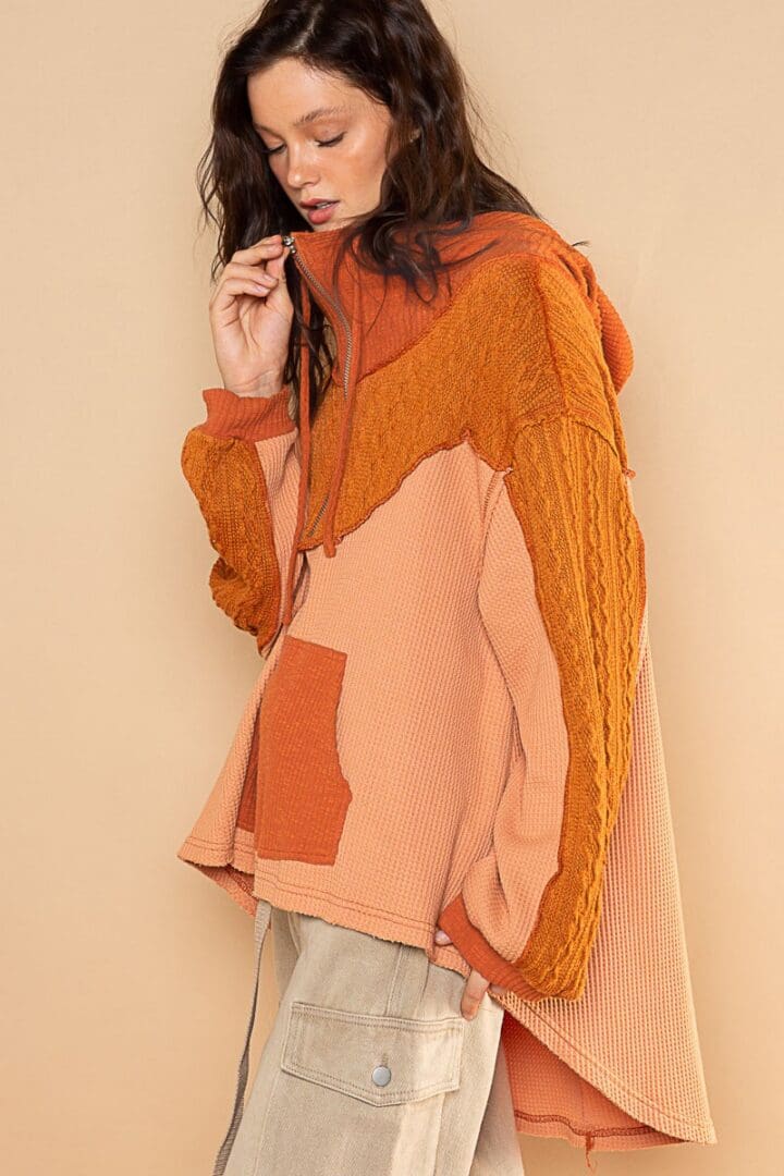 Woman in orange and peach patchwork hoodie.