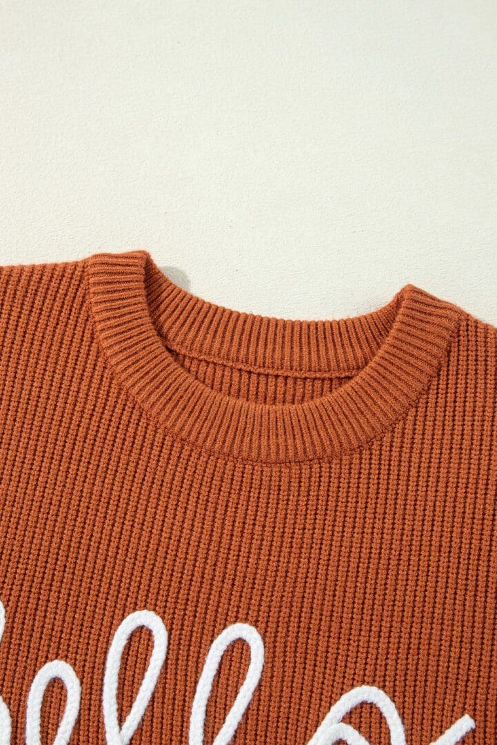 Orange knit sweater with "hello" detail.