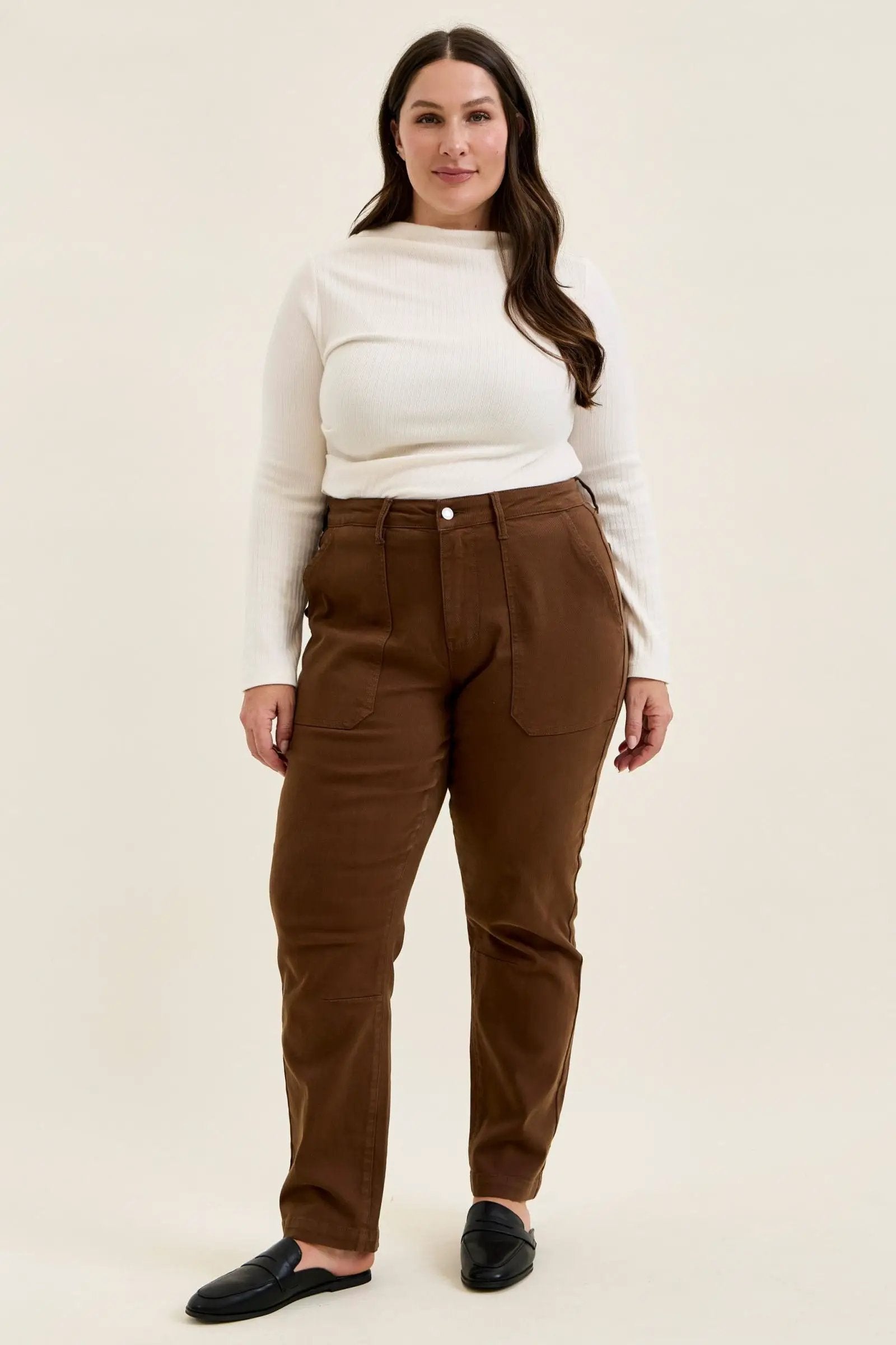 Plus size model wearing mahogany high-waist stretch jeans with utility pockets and slim-straight leg in double-rolled cuffs.