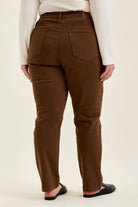 Back view of mahogany high-waist plus stretch jeans with utility pockets and slim-straight legs, styled with black loafers.