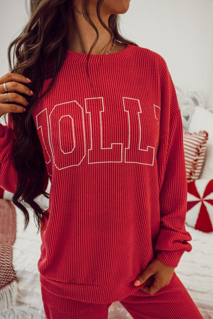 A person standing in front of a wall wearing a red sweater.