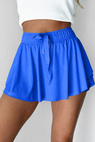 Blue skirt with a tie waist worn by a person on a plain background