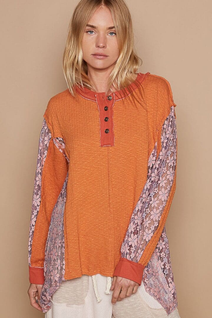 Orange henley top with lace sleeves.