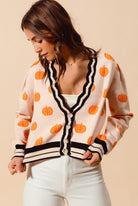 A woman in white shirt and orange polka dot cardigan.