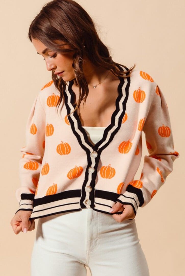 A woman in white shirt and orange polka dot cardigan.