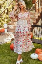 A woman standing in front of pumpkins wearing a dress.