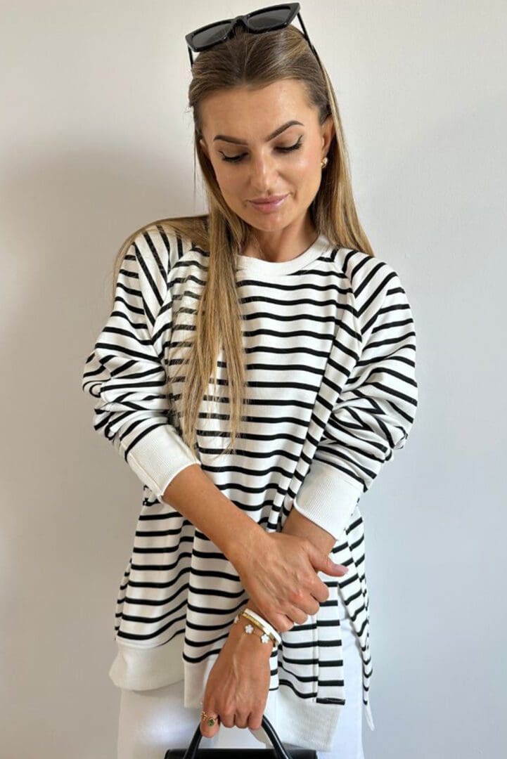 A woman in black and white striped shirt holding a knife.