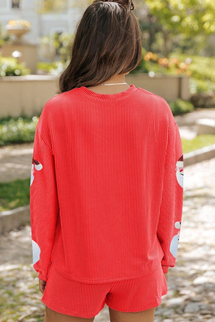 A woman wearing an orange sweater with santa clause on it.