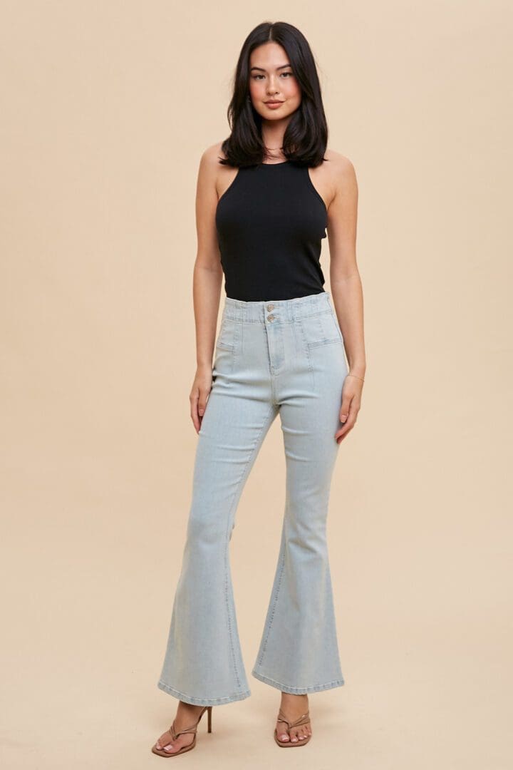 A woman wearing light blue jeans and black top.